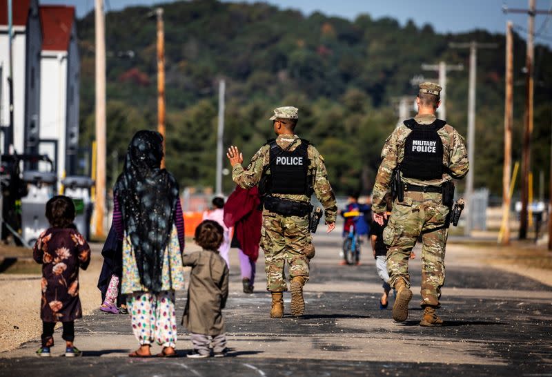 U.S. Military Police walk past Afghan refugees at the Village at Fort McCoy U.S. Army base