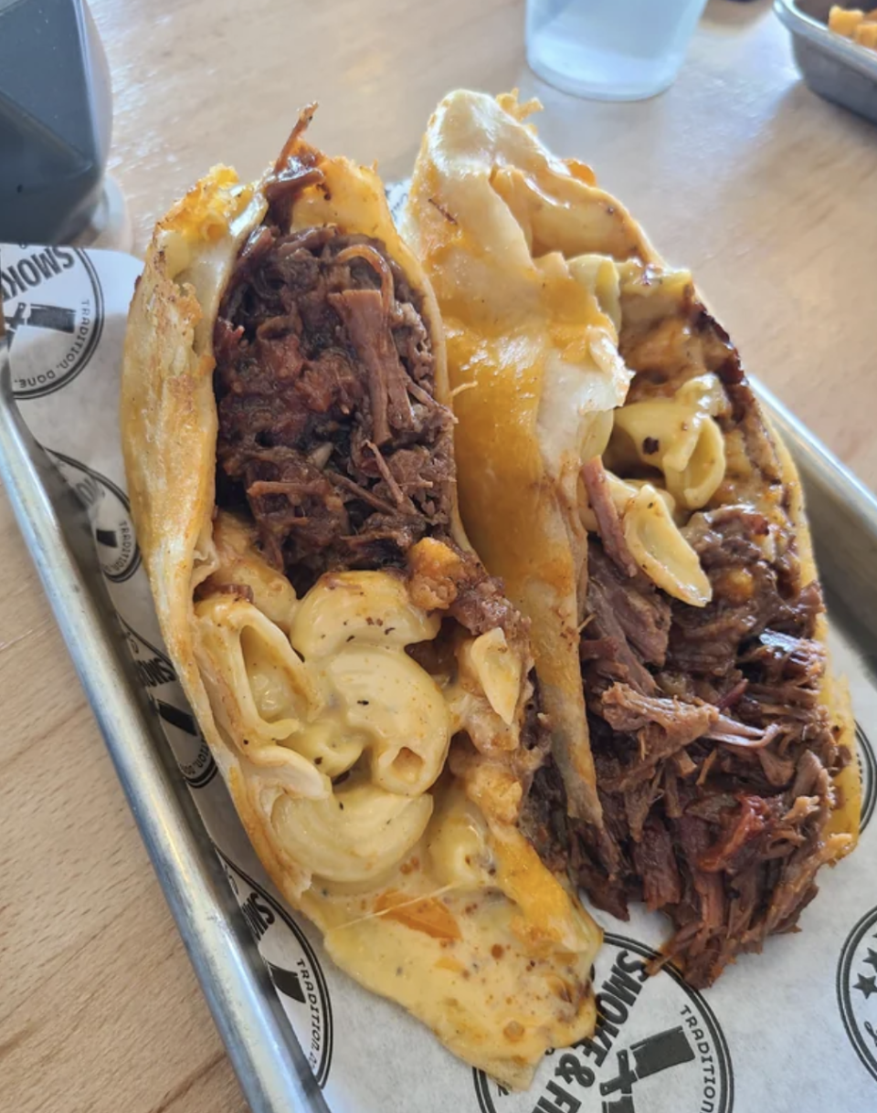 A taco shell is filled with mac and cheese and brisket