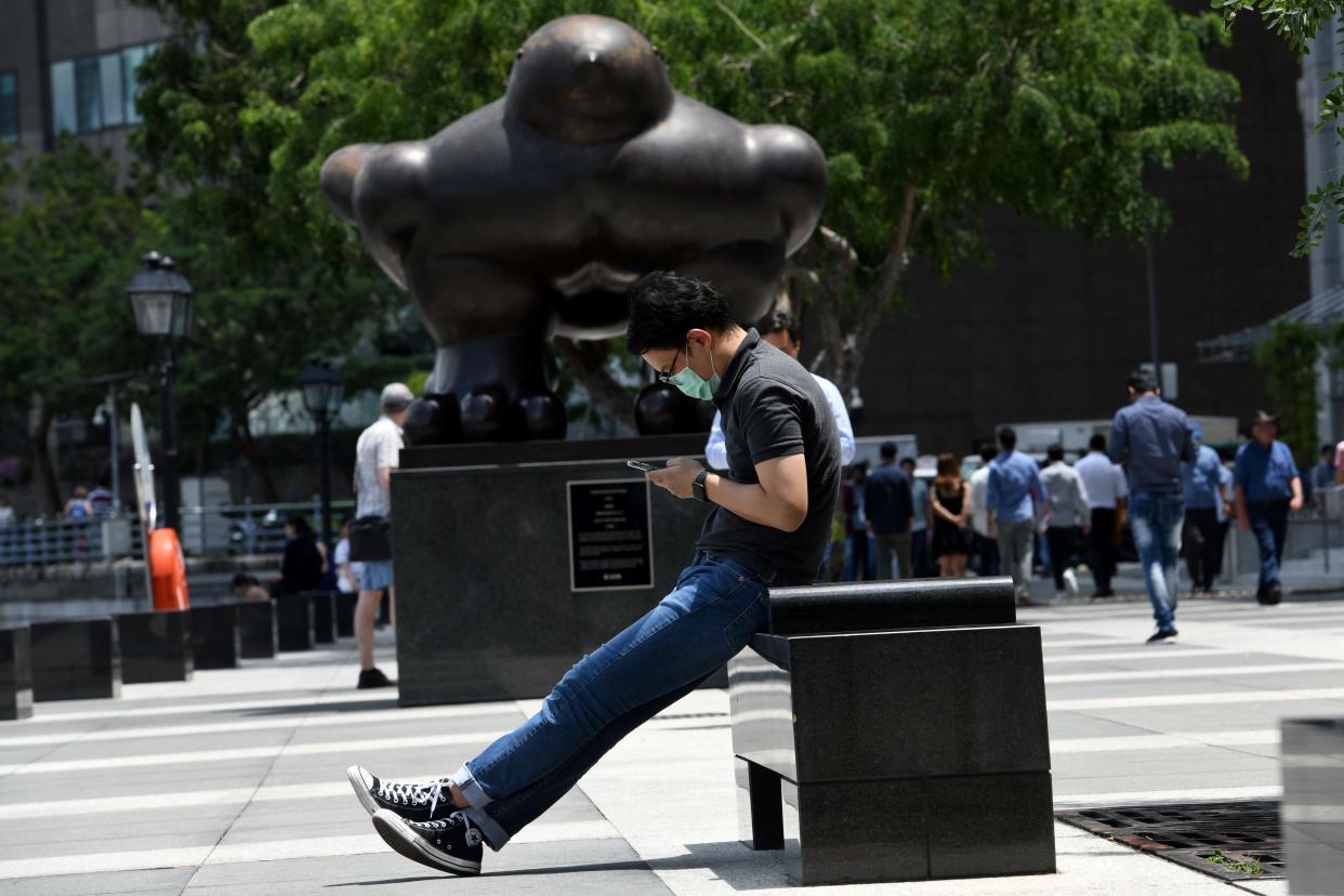 A man wearing a protective facemask, amid concerns over the spread of the COVID-19 coronavirus, looks at his smartphone in Singapore on February 14, 2020. (Photo by Roslan RAHMAN / AFP) (Photo by ROSLAN RAHMAN/AFP via Getty Images)