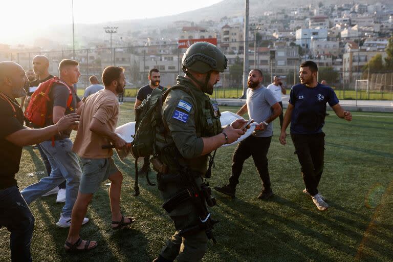 Traslado de víctimas en la cancha de fútbol de Majdal Shams en los Altos del Golán. (Jalaa MAREY / AFP)