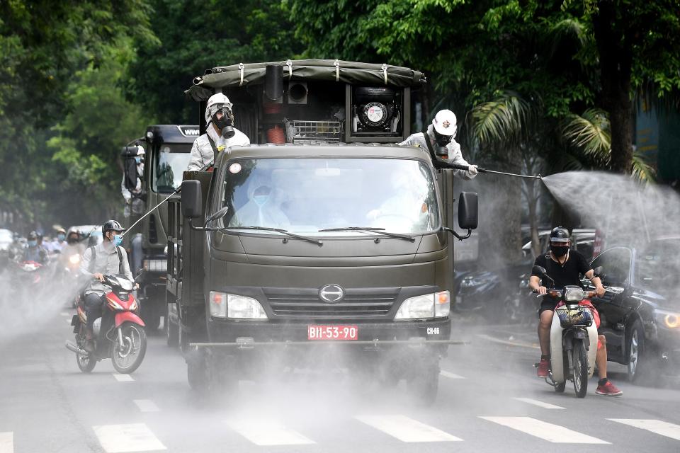 Military personnel spray disinfectant on a street in Hanoi on July 26, 2021 as a preventive measure to stop the spread of the Covid-19 coronavirus. (Photo by Nhac NGUYEN / AFP) (Photo by NHAC NGUYEN/AFP via Getty Images)