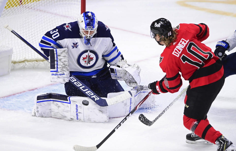 Winnipeg Jets goaltender Laurent Brossoit (30) makes a save on Ottawa Senators' Ryan Dzingel (10) during the second period of an NHL hockey game Wednesday, April 14, 2021, in Ottawa, Ontario. (Sean Kilpatrick/The Canadian Press via AP)