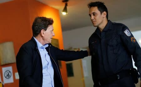 Senator Marcelo Crivella, candidate for Rio de Janeiro mayor, greets a policeman after voting during the municipal elections at a polling station in Rio de Janeiro, Brazil, October 30, 2016. REUTERS/Ricardo Moraes