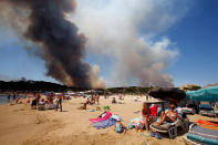 <p>Smoke fills the sky above a burning hillside as tourists relax on the beach in Bormes-les-Mimosas, in the Var department, France, July 26, 2017. (Jean-Paul Pelissier/Reuters) </p>