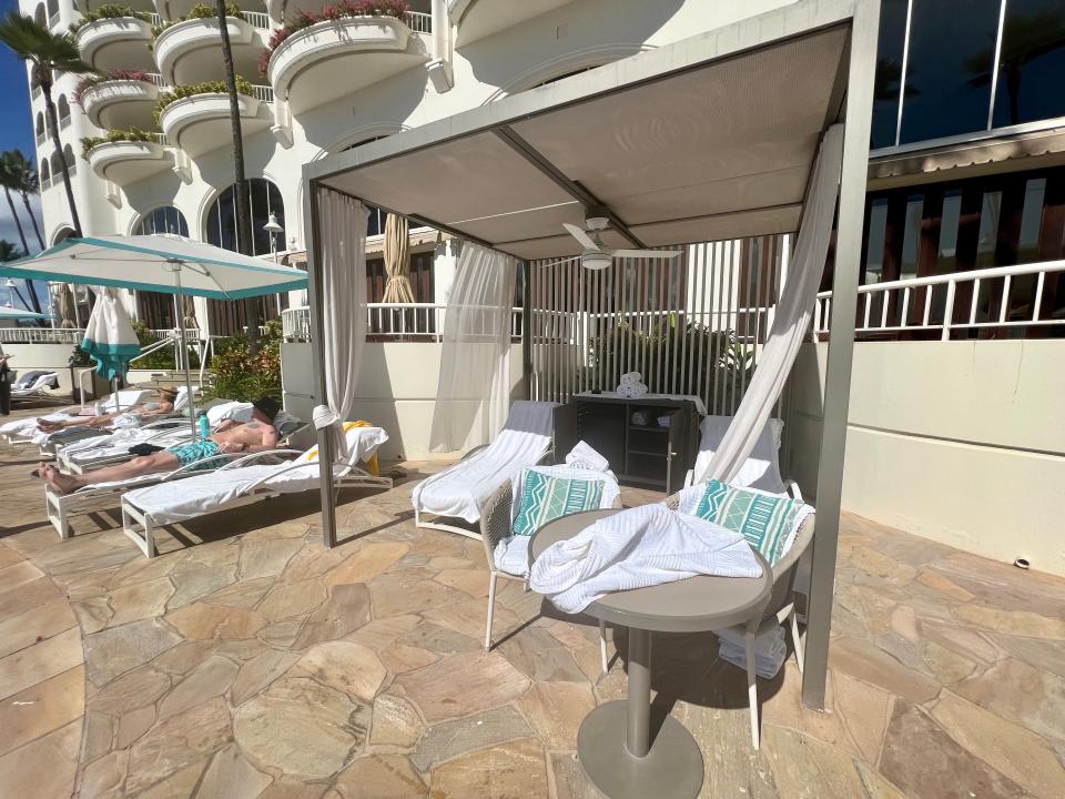 cabanas with chairs inside next to poool