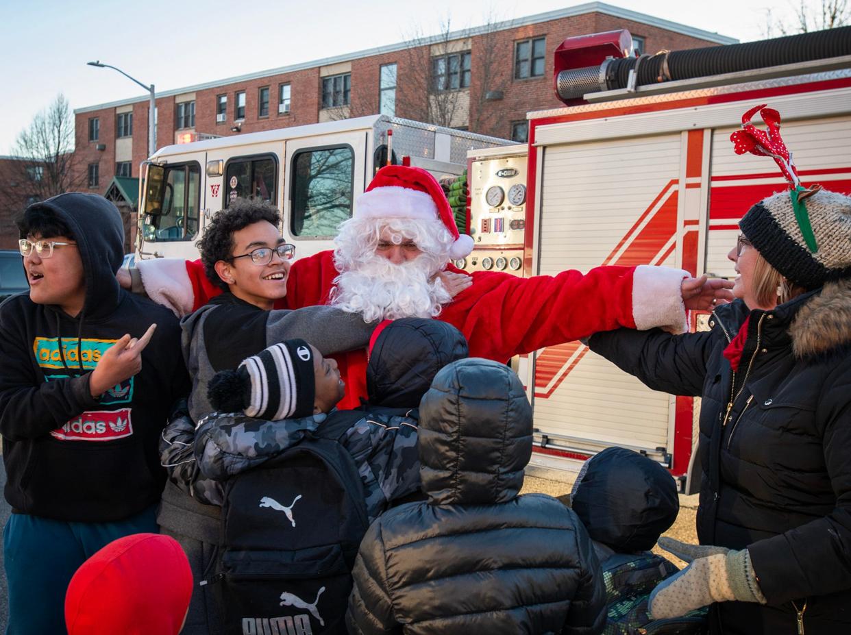 Santa Claus gets is surrounded by children as he arrives at Great Brook Valley Thursday on a firetruck.