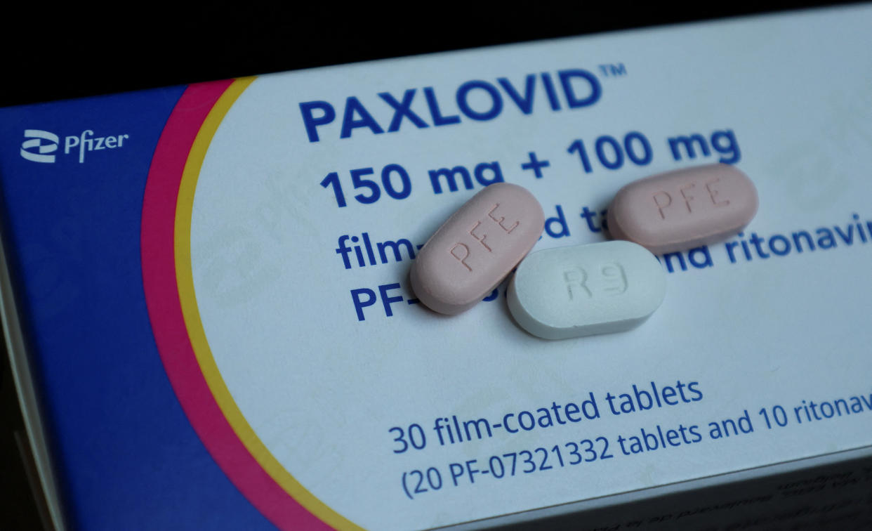 Paxlovid pill box with three pills printed with PFE and R9 resting on it.