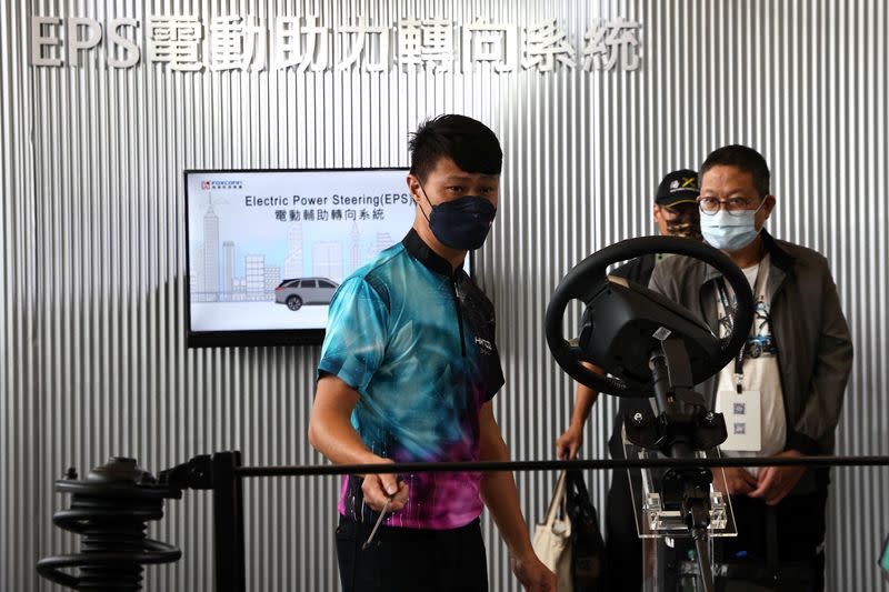 A staff explains an electric power steering system to a guest during Foxconn's annual Tech Day in Taipei