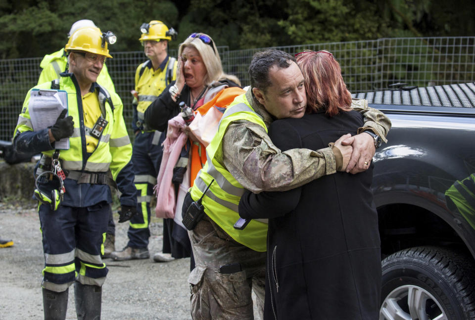 In this image released by the Pike River Recovery Agency, Dinghy Pattinson, left, stands with, Sonya Rockhouse, as Karl Maddaford embraces Anna Osborne before the re-entry the Pike River Mine, near Greymouth on the West Coast of New Zealand, Tuesday, May 21, 2019. Crews in New Zealand on Tuesday reentered an underground coal mine where a methane explosion killed 29 workers more than eight years ago, raising hopes among family members that they might find bodies and new evidence that leads to criminal charges. (Neil Silverwood/Pike River Recovery Agency via AP)