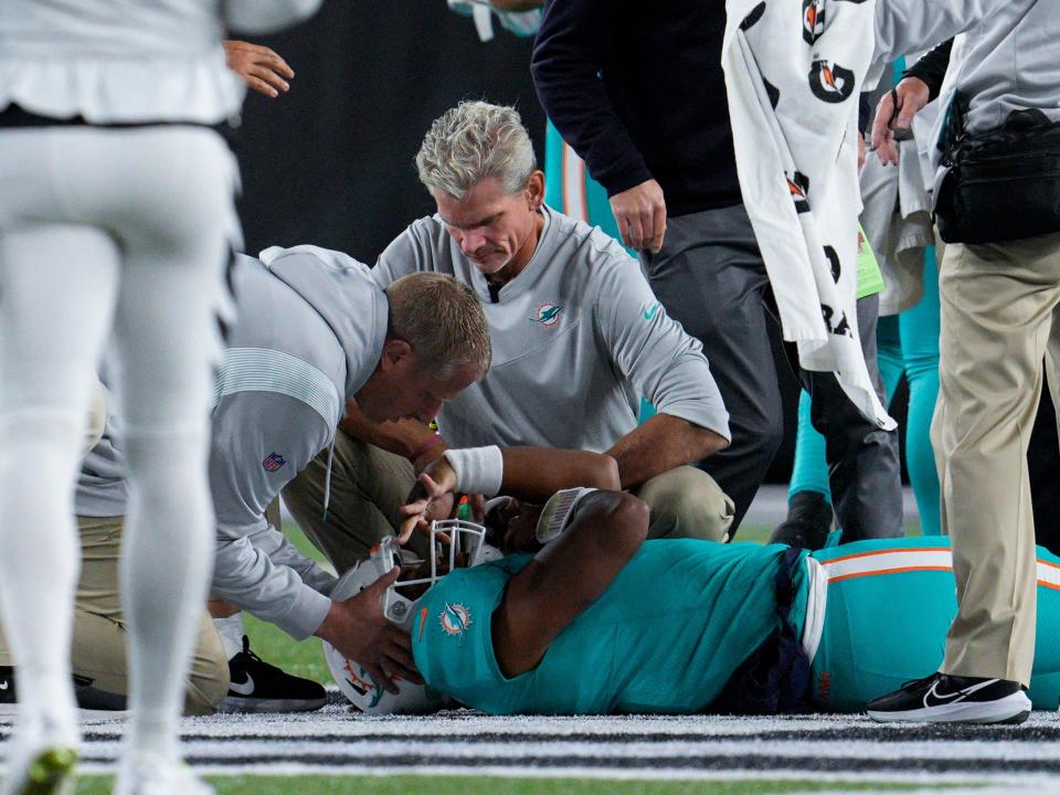 Miami Dolphins quarterback Tua Tagovailoa lies on the field as he is attended to by medical professionals.