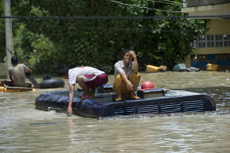 Flood-inundated residents look on from the roof of a vehicle in Kalay, upper Myanmar's Sagaing region, on August 2, 2015