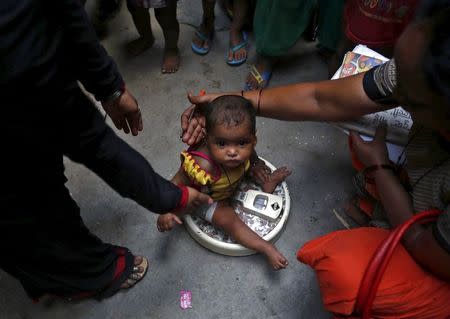 A health worker (R) weighs a child under a government program in New Delhi, India, May 7, 2015. REUTERS/Anindito Mukherjee