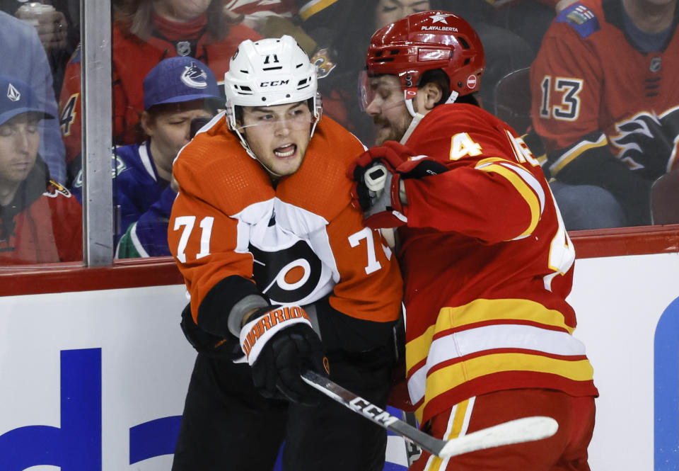 Philadelphia Flyers forward Tyson Foerster, left, is checked by Calgary Flames defenseman Rasmus Andersson, right, during first-period NHL hockey game action in Calgary, Alberta, Sunday, Dec. 31, 2023. (Jeff McIntosh/The Canadian Press via AP)