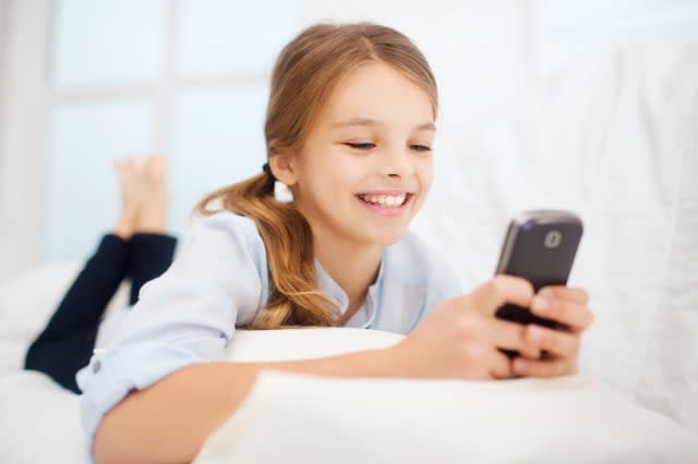 education, school, technology and internet concept - little student girl with smartphone at home