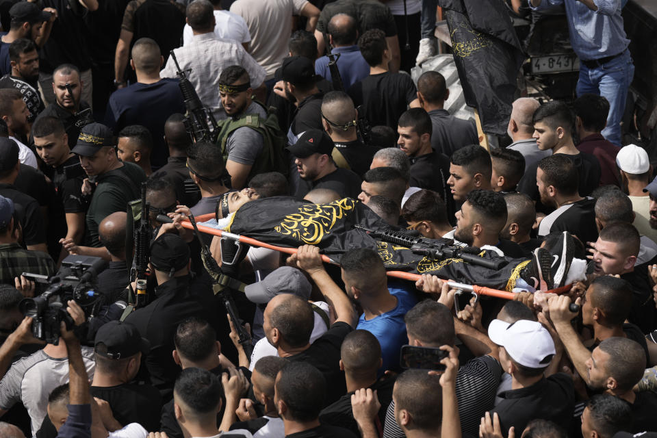 ADDS ISLAMIC JIHAD FLAG DESCRIPTION - Mourners carry the body of Matin Dababa, draped in the flag of the Islamic Jihad militant group, at his funeral in the Jenin refugee camp, Friday, Oct. 14, 2022. The Palestinian Health Ministry says the Israeli military shot and killed two Palestinians, including Dababa, during a raid into the Jenin refugee camp in the occupied West Bank. (AP Photo/ Majdi Mohammed)