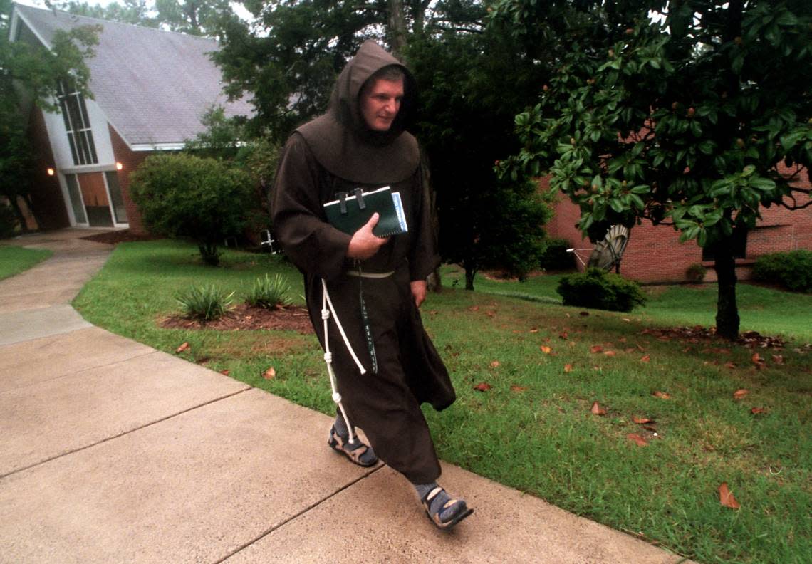 Father Patrick Tuttle uses his Franciscan robe to fight off the wet weather while making some of his daily rounds in 1999.