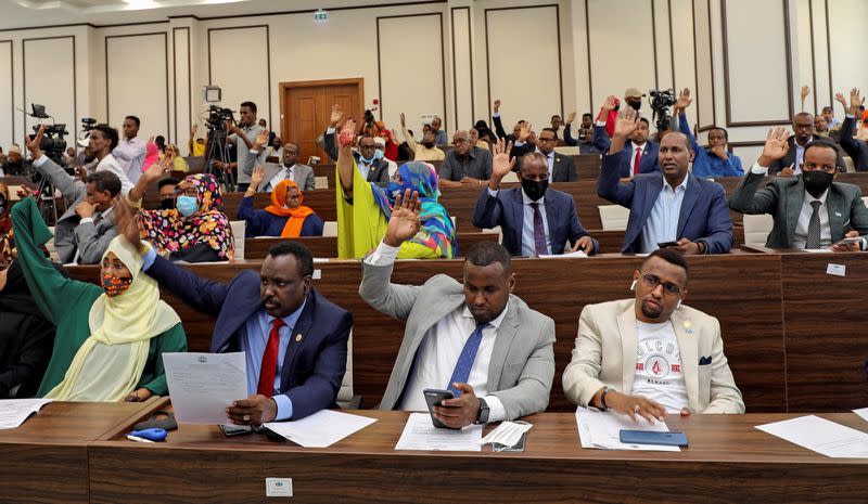 FILE PHOTO: Somalia legislators vote by rising their hands to cancel a divisive two-year presidential term extension, inside the lower house of Parliament in Mogadishu