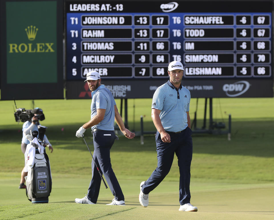 Dustin Johnson, left, and Jon Rahm check out their shots on the 18th green during the first round of the Tour Championship golf tournament at East Lake Golf Club on Friday, Sept. 4, 2020, in Atlanta. (Curtis Compton/Atlanta Journal-Constitution via AP)