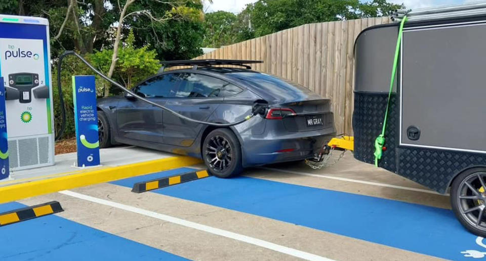 Dark grey Tesla towing caravan charging vehicle at BP Pulse charging bay. 