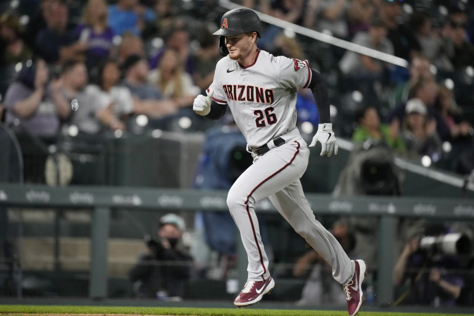 Arizona Diamondbacks' Pavin Smith scores on a sacrifice fly hit by Josh Rojas off Colorado Rockies relief pitcher Jordan Sheffield in the eighth inning of a baseball game Friday, May 21, 2021, in Denver. (AP Photo/David Zalubowski)