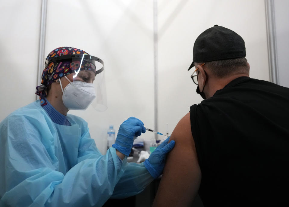 A medical worker administers a shot of Pfizer COVID-19 vaccine to Vitaly Pavlov from Rostov-on-Don at Belgrade Fair makeshift vaccination center in Belgrade, Serbia, Saturday, Oct. 2, 2021. Pavlov looked for a vaccine that would allow his family to travel freely — a quest that brought them to Serbia, where hundreds of Russian citizens have flocked in recent weeks to receive Western-approved COVID-19 shots. (AP Photo/Darko Vojinovic)