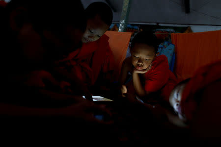 Boys play with their mobile phones and tablets at Wat Klang Thung temple where they temporarily live after entering Buddhist novicehood, in Mae Hong Son, Thailand, April 15, 2018. REUTERS/Jorge Silva