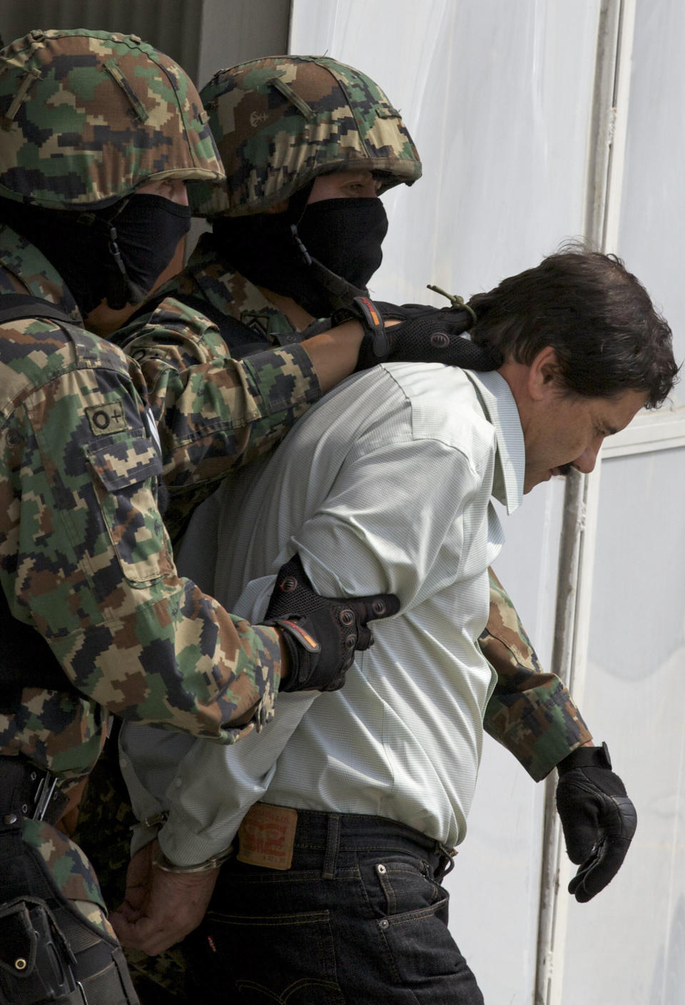 Joaquín "El Chapo" Guzmán es escoltado con las esposas puestas a un helicóptero por infantes de Marina mexicanos en un hangar de la Marina en la Ciudad de México el sábado 22 de febrero de 2014. (Foto AP/Darío López-Mills)