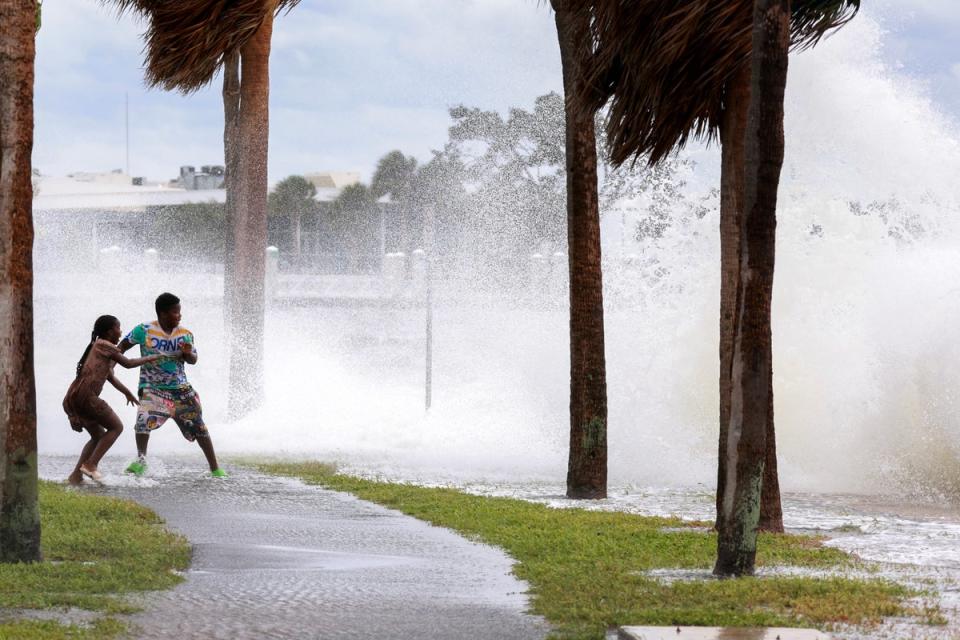 <p>People are splashed by churning surf from Tampa Bay as Hurricane Helene passes offshore</p> (Getty Images)