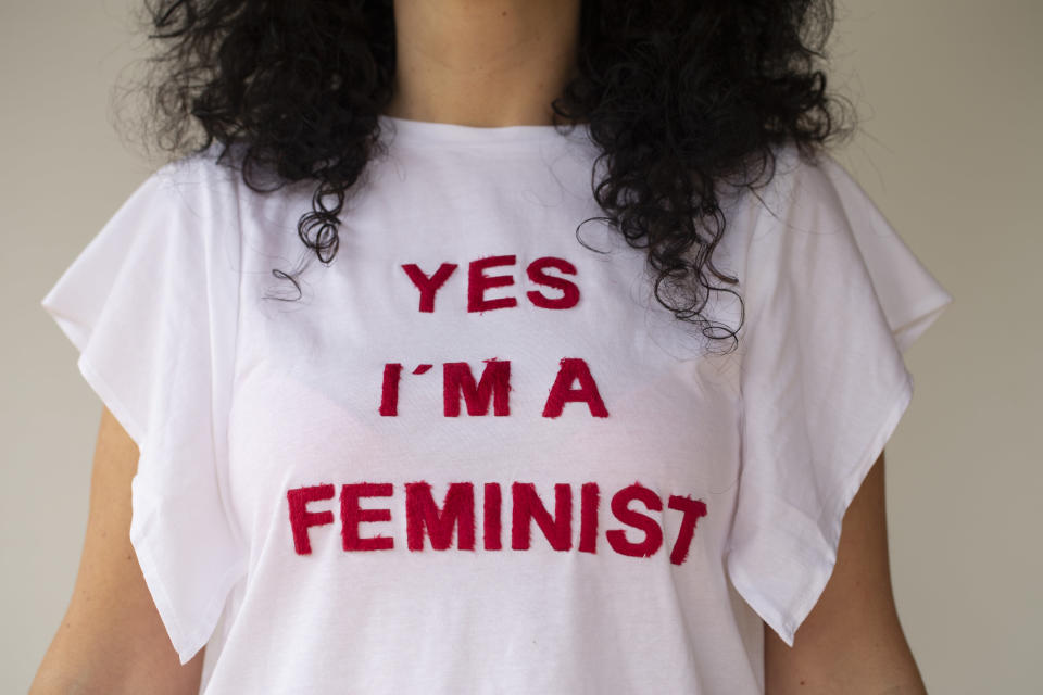 close up of a woman wearing a tee shirt that reads "yes I'm a feminist"