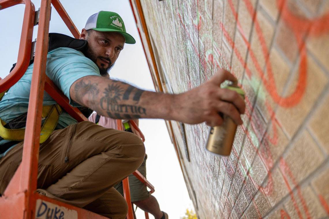 Rodrigo “Rico” Alvarez doodles a design with spray paint while starting work on the mural at the Mattie Rhodes Center.