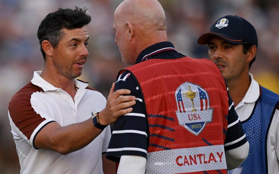 Rory McIlroy of Europe speaks to Joe LaCava, caddie for Patrick Cantlay of USA,