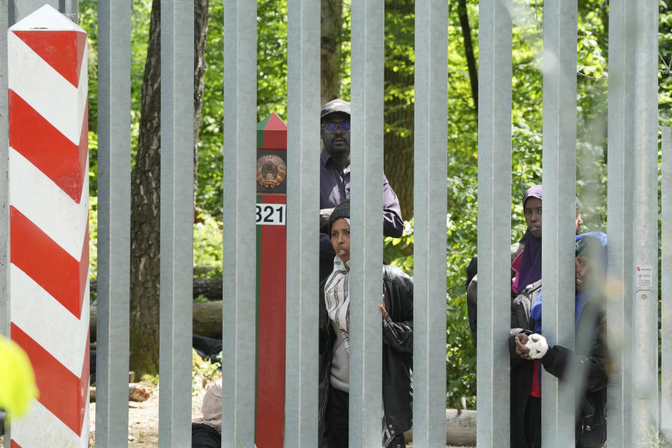 A view of migrants behind the metal barrier border that Poland has erected along the border with Belarus, in Bialowieza Forest, on Wednesday, May 29, 2024. Poland says neighboring Belarus and its main supporter Russia are behind a surging push by migrants in Belarus toward the European Union. (AP Photo/Czarek Sokolowski)