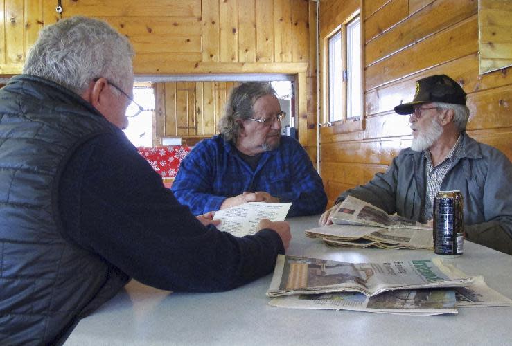 in this Dec. 13, 2016 photo Serge Myers, right, speaks to George Niland, center, as their attorney, Monte Beck reads a legal document in Opportunity, Mont. Niland and Myers are among the dozens of residents of this small community who are suing for the right to clean the toxic metals left by the smelter from their yards and claim federal environmental officials and the smelter's owner have botched a 34-year cleanup. (AP Photo/Matt Volz)