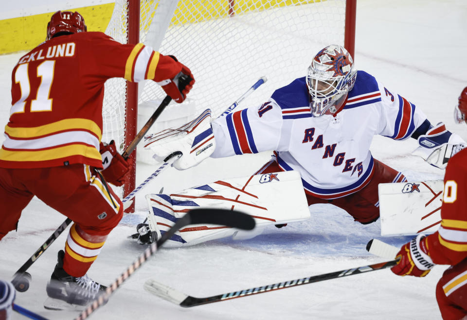 New York Rangers goalie Igor Shesterkin, right, stops Calgary Flames forward Mikael Backlund during the third period of an NHL hockey game Tuesday, Oct. 24. 2023, in Calgary, Alberta. (Jeff McIntosh/The Canadian Press via AP)