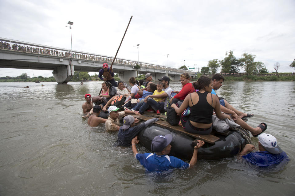 A group of Central American migrants cross the Suchiate River aboard a raft made out of tractor inner tubes and wooden planks, on the the border between Guatemala and Mexico, in Ciudad Hidalgo, Mexico, Saturday, Oct. 20, 2018. After Mexican authorities slowed access through the border bridge to a crawl, hundreds of migrants are boarding the rafts or wading across the river and crossing into Mexico illegally. (AP Photo/Moises Castillo)