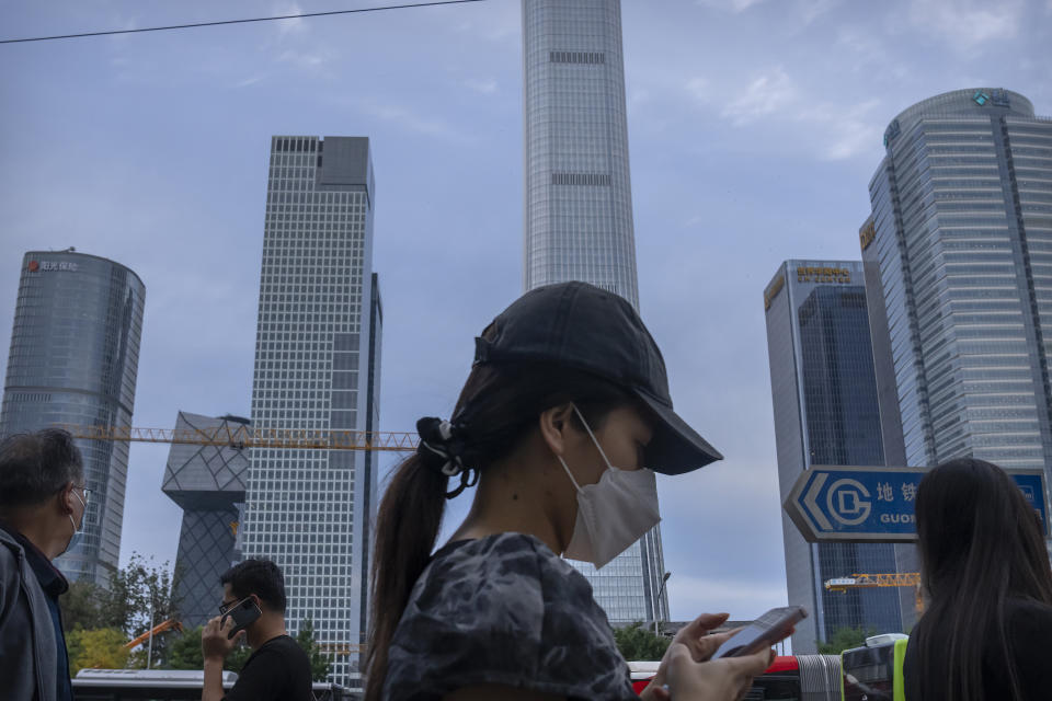 People wearing face masks to protect against COVID-19 walk along a street in the central business district in Beijing, Thursday, Sept. 16, 2021. China on Thursday reported several dozen additional locally-transmitted cases of coronavirus as it works to contain an outbreak in the eastern province of Fujian. (AP Photo/Mark Schiefelbein)