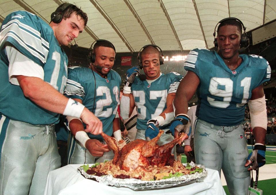 Detroit Lions from left Gus Frerotte (L), Greg Hill, Johnnie Morton and Robert Porcher get to sample FOX TV's Jon Madden's turkeys after their game against the Chicago Bears on Nov. 25, 1999 in Pontiac, Michigan. (Photo by JEFF KOWALSKY/AFP via Getty Images)