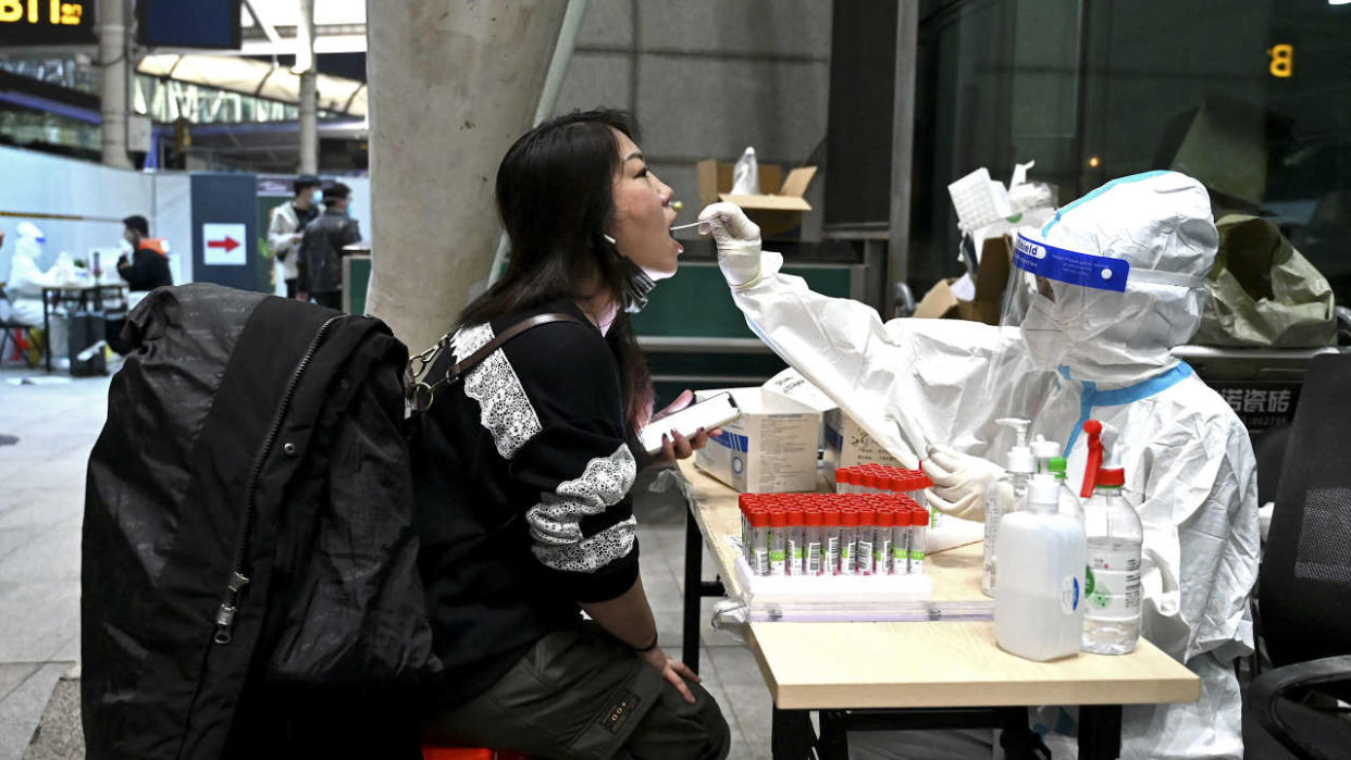 A health worker gets a swab sample from an arriving passenger as a preventive measure against the Covid-19 coronavirus at the Guangzhou Baiyun International Airport in China's southern Guangdong province on March 21, 2022. (Photo by Noel Celis / AFP)