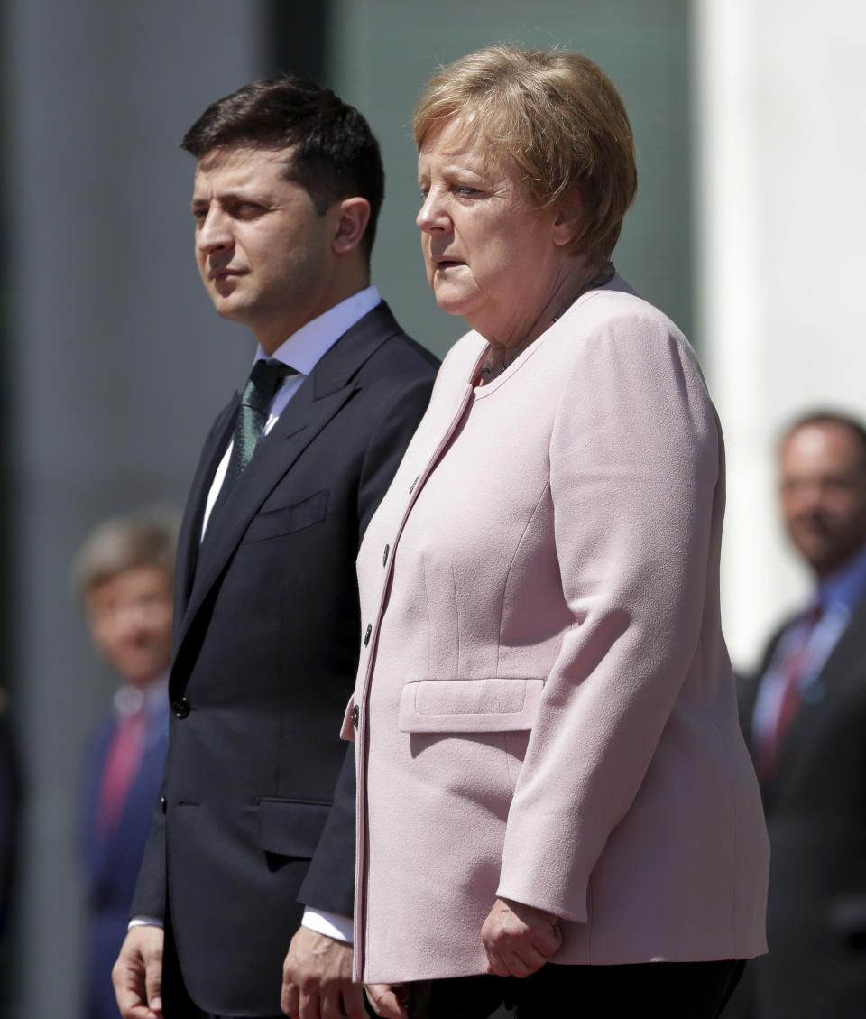 German Chancellor Angela Merkel, right, trembles strong as she and Ukraine's President Volodymyr Zelenskiy, left, attend the national anthems as part of a military welcome ceremony in Berlin, Germany, Tuesday, June 18, 2019. Merkel appeared unwell as she met with Zelenskiy in Berlin, visibly shaking as she received the new Ukrainian president at the chancellery. The incident came Tuesday afternoon as the two stood outside Merkel's office in the hot weather while a military band played their national anthems. Merkel's office had no immediate comment and the two were to hold a press conference later in the afternoon. Following the anthems Merkel seemed better, walking along the red carpet with Zelenskiy into the building, pausing to greet the military band and take a salute. Merkel turns 65 next month. (AP Photo/Michael Sohn)