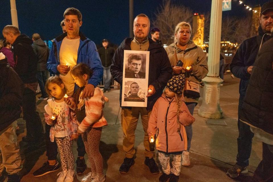 Parents protest the deaths of Russian opposition leaders, holding pictures of Alexei Navalny and Boris Nemtsov, with their children at a candlelight vigil along the Sacramento waterfront on Tuesday. Renée C. Byer/rbyer@sacbee.com