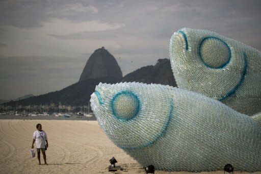 A woman looks at an installation made of recycled plastic bottles representing fishes in Rio de Janeiro. After exhausting negotiations concluding on the eve of a global summit, UN members on Tuesday backed a plan for nursing Earth's sick environment back to health and tackling poverty through greener growth