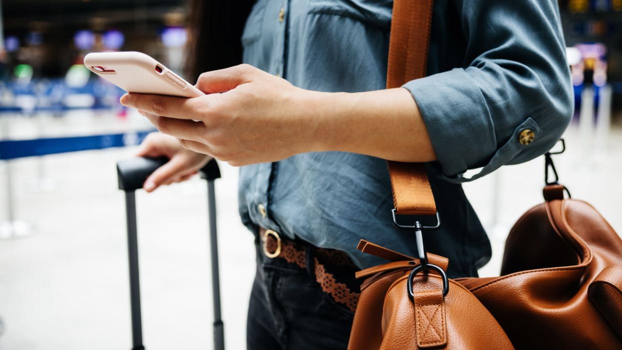  A close-up of a woman in an airport using a smartphone. 