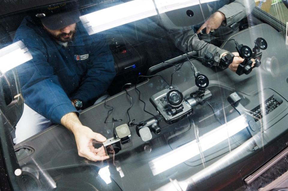 two individuals in a car testing dashcams mounted to the windshield