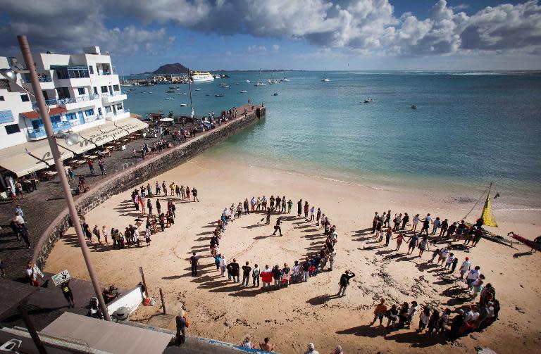 People form a giant S.O.S. on a beach as they protest against oil exploration being carried off the coast of the Canary Islands, in Corralejos on November 30, 2014