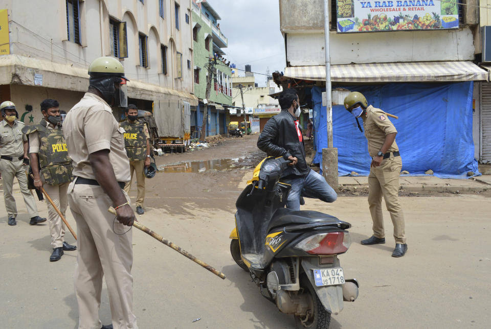 A policeman thrashes a motorist for violating prohibitory orders a day after violent protests in Bengaluru, India, Wednesday, Aug. 12, 2020. At least three people have died in the southern Indian city also known as Bangalore after hundreds of demonstrators clashed with the police overnight against a Facebook post considered offensive to Muslims, attacking a police station and setting fire to vehicles, police said Wednesday. (AP Photo)