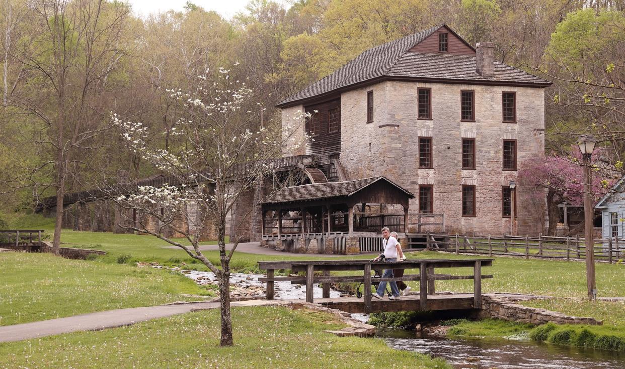 Visitors head over the bridge in the Pioneer Village at Spring Mill State Park on April 19, 2017. There are a variety of events conducted in the village each year and visitors can walk through many of the buildings, including the gristmill.