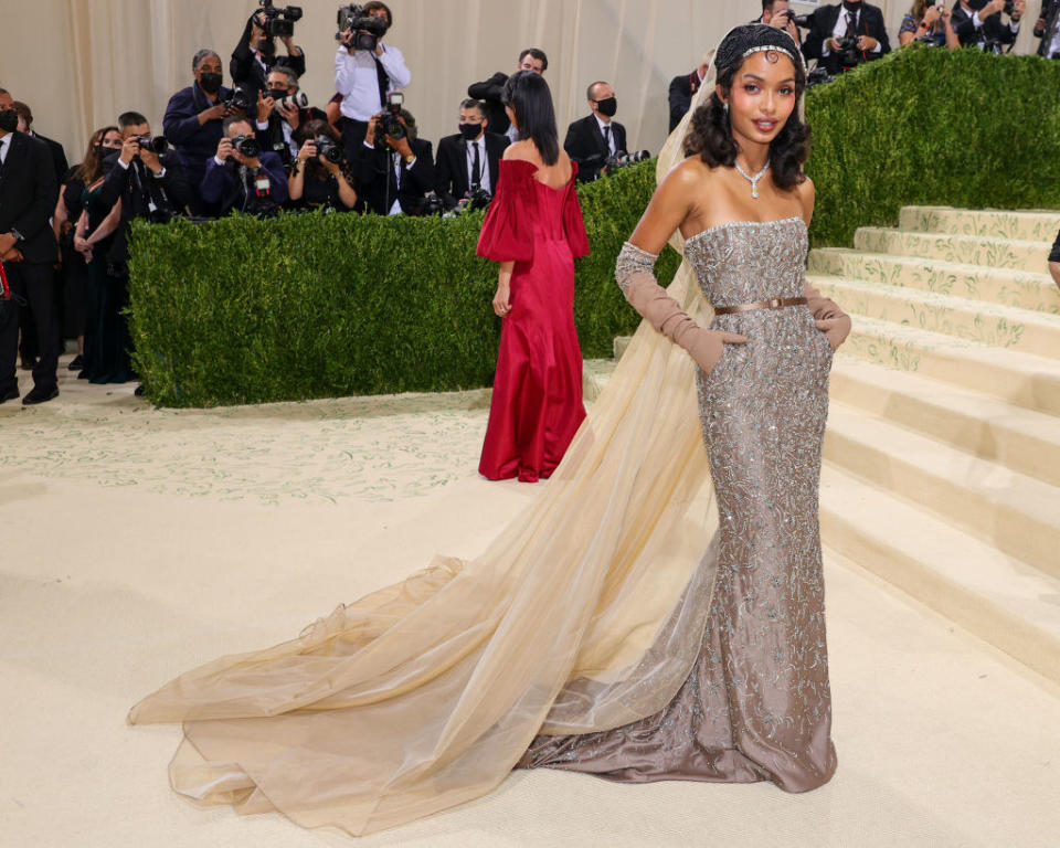Yara Shahidi attends The 2021 Met Gala Celebrating In America: A Lexicon Of Fashion in a strapless sequined gown with veil that transitioned into a long train