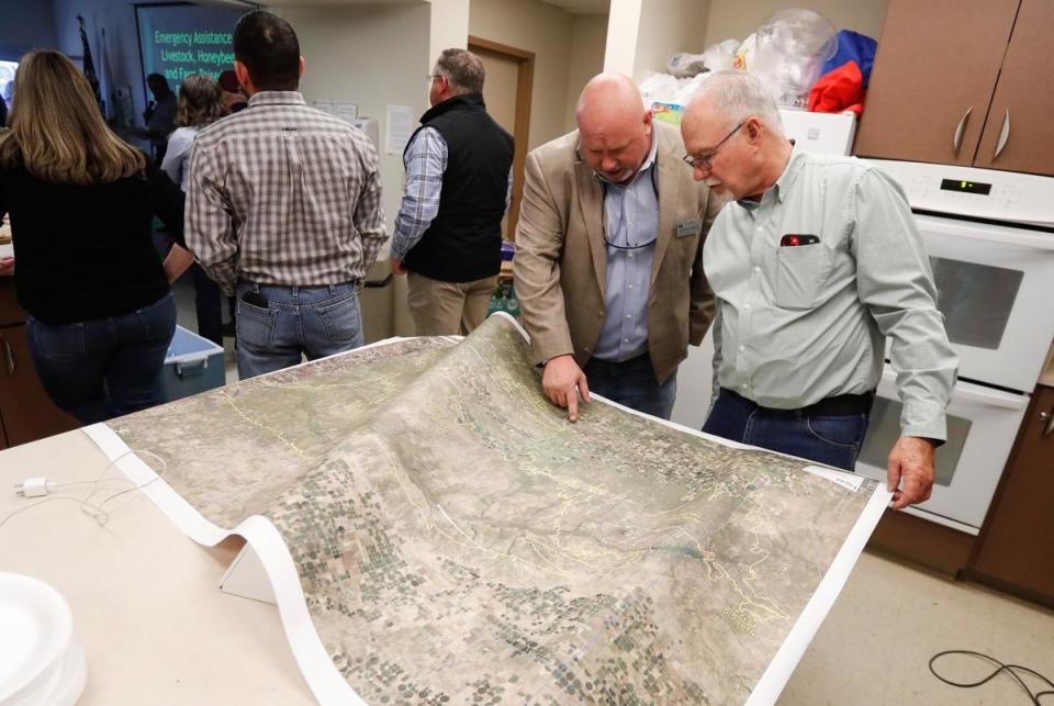 From left: Joe Dan Ledbetter and Rick Hargrove look over a map showing the burn site at the Hemphill County Exhibition center in Canadian on March 5, 2024. Ranchers, livestock producers and land owners attended a USDA informational meeting meeting to help people affected by the panhandle fires.