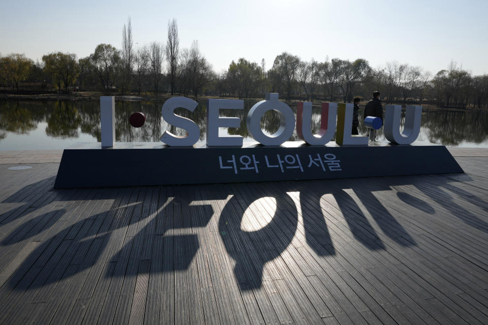 FILE - Visitors wearing face masks to help curb the spread of the coronavirus walk near the display of South Korea's capital Seoul logo in Seoul, South Korea, on Dec. 8, 2021. (AP Photo/Lee Jin-man, File)