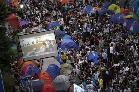 Pro-democracy protestors watch formal talks between student protest leaders and city officials on a video screen near the government headquarters in Hong Kong October 21, 2014. REUTERS/Carlos Barria